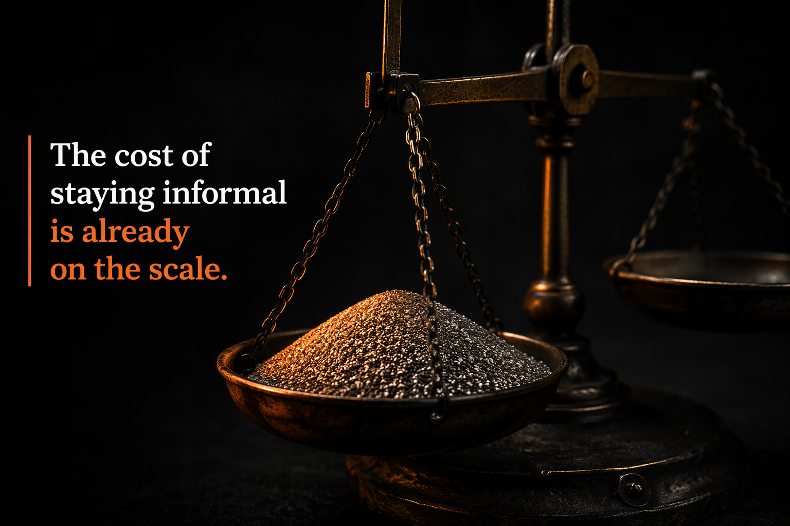A macro close-up of a worn brass balance scale, one pan weighted with fine grey sand illuminated by a single warm orange light, the other pan empty and in shadow — against a near-black charcoal background.