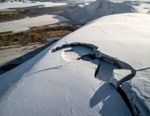 A polished stone surface appears pristine from above while deep structural cracks are revealed at its edge, representing the gap between compliance appearances and the underlying IT control failures that remain invisible until audit scrutiny arrives.