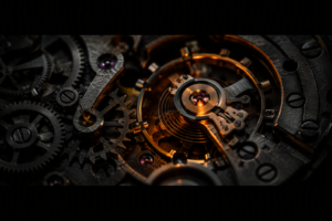 An ultra-close-up of an exposed mechanical clock movement with dark steel gears and springs, a single warm orange light illuminating the central escapement wheel against a near-black background