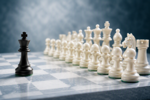A black chess king standing alone opposite a complete set of white chess pieces on a chessboard, symbolising an independent IT managed service provider in a consolidating market.